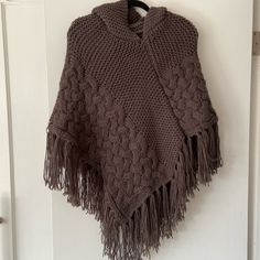 a brown knitted ponchle hanging on a white door