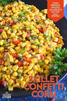 a black plate topped with corn and veggies on top of a blue table