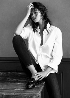 a black and white photo of a woman sitting on a table with her hands in her hair