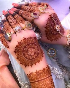 two hands with henna tattoos on them and some rings in the middle of each hand