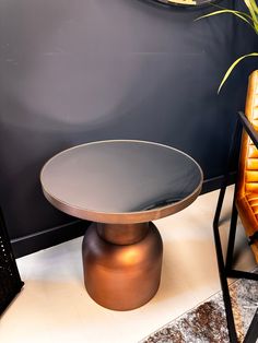 a chair and table in front of a wall with a potted plant on it