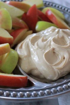 a plate filled with apples and dip next to some other fruit on a silver platter