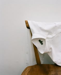 a white shirt sitting on top of a wooden chair with the letter h on it