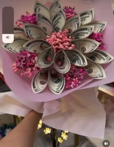 a bouquet made out of dollar bills and pink flowers