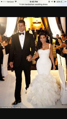 a man and woman dressed in formal wear walking down the aisle at an event together