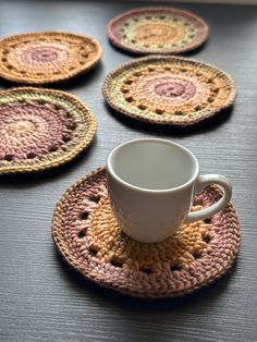 crocheted coasters are arranged around a coffee cup