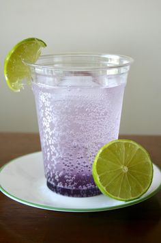 a purple drink with lime slices on the rim