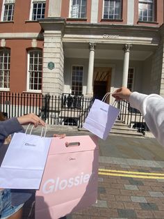 two people holding shopping bags in front of a building