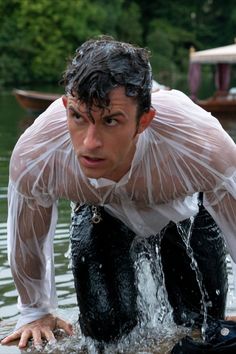 a man in wetsuit crouches down to take a plunge into the water with his hands on his hips