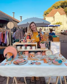 a woman standing next to a table filled with plates and cups