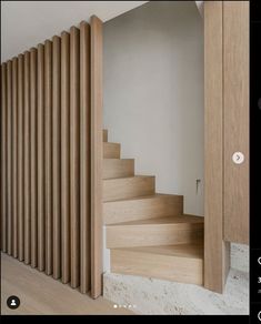 a wooden stair case next to a white wall