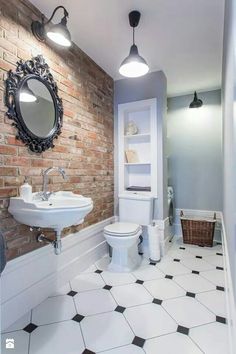 a bathroom with a toilet, sink and mirror on the wall next to a brick wall