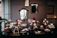 a table filled with desserts and pastries next to a mirror