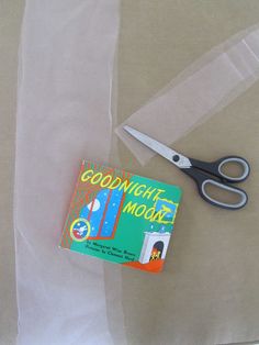 a pair of scissors sitting on top of a table next to a package of tape