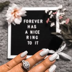 a woman's hand with white manies and a ring on her finger next to a sign that says forever has a nice ring to it