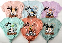 four shirts with mickey mouse on them sitting next to each other in front of a white wall