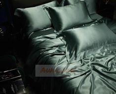 a bed covered in green sheets and pillows