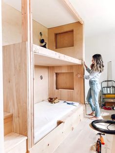 a woman standing on top of a wooden bunk bed