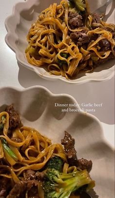 two white bowls filled with noodles and meat on top of a table next to each other