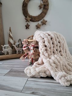 a pile of blankets sitting on top of a wooden floor next to a christmas wreath