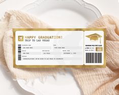 a white plate topped with a gold ticket and a graduation cap on top of it