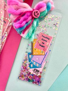 there is a bookmark with a pink and blue hair bow on top of it