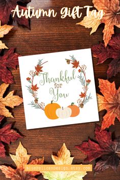 an autumn gift tag with leaves and pumpkins around it on a wooden table surrounded by fall leaves