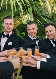 a group of men in tuxedos toasting each other with glasses of orange juice