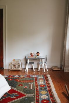 a room with a rug, two chairs and a table on the floor in front of it