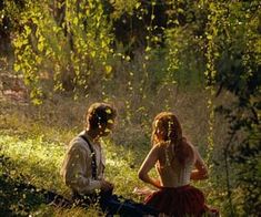 two people sitting in the grass near trees