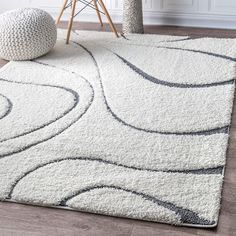 a white rug with black and grey swirls on the floor next to a chair