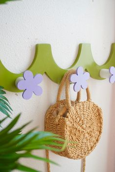 a purse hanging on the wall next to a potted plant