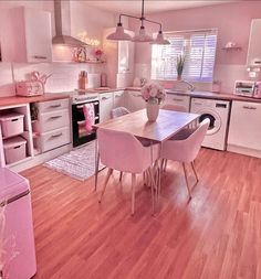 a kitchen filled with lots of pink furniture and decor on top of hard wood flooring