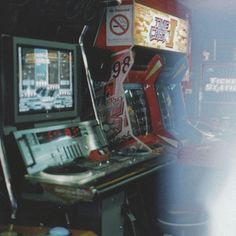 an old fashioned video game machine sitting on top of a table next to a neon sign