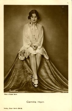 an old black and white photo of a woman sitting on top of a cloth covered chair