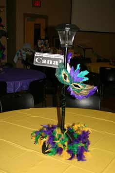 a table topped with a purple and green feathered centerpiece next to a street sign