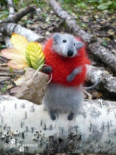 a stuffed animal mouse holding an autumn leaf