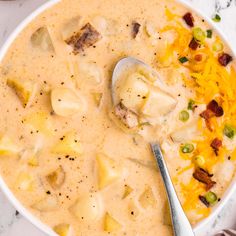 a white bowl filled with potato soup and topped with bacon, cheese and green onions