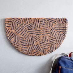 a blue and brown rug sitting on top of a white wall next to a backpack