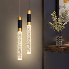 two black and gold lights hanging from a wall next to a vase with flowers in it