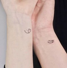 two small wrist tattoos with hearts and arrows on each one arm, both in black ink