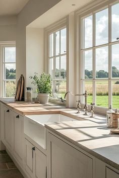 a kitchen filled with lots of windows next to a white sink and counter top under a window