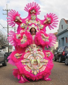 a woman in pink and gold costume walking down the street