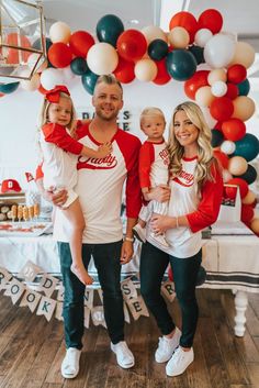 a man, woman and two children standing in front of balloons