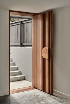 an open door with a wooden handle in front of some steps and a fence on the other side