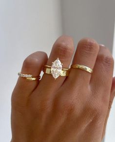 a woman's hand with two gold rings and one diamond ring on her finger