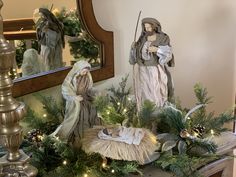 a nativity scene is displayed in front of a mirror with lights on the mantle