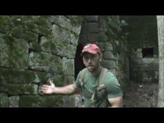 a man standing in front of a stone wall with his hands out to the side