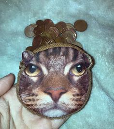 a coin purse with a cat's face on it and coins in the background