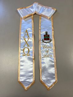 two white and gold graduation sashes with the words class of 2013 on them, hanging from a wall